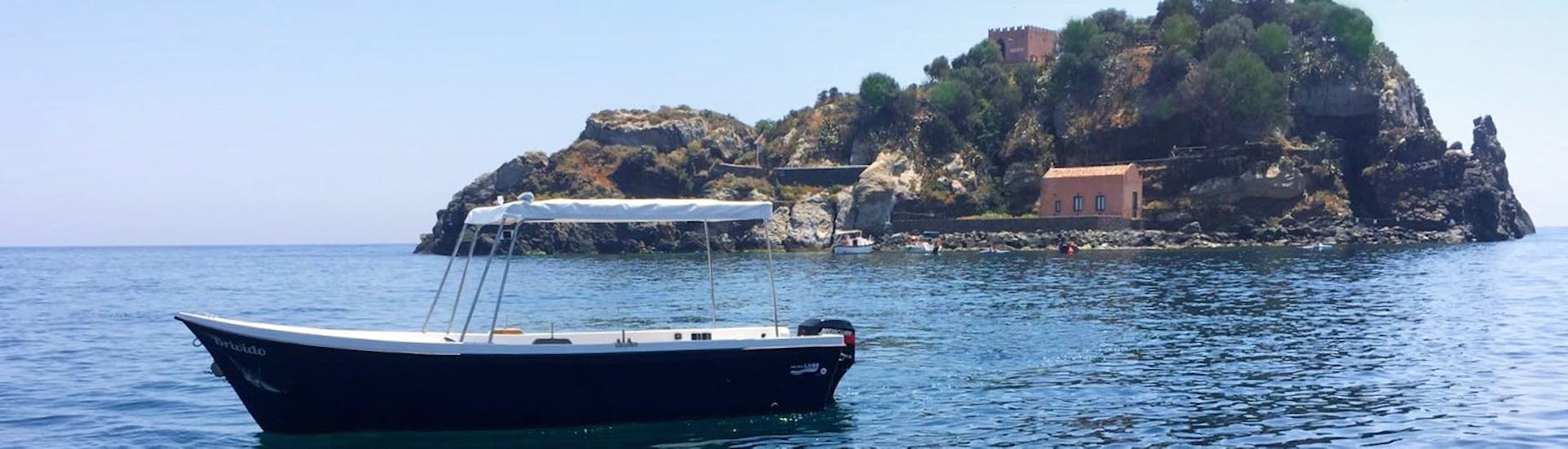 Le bateau de Navigando per Trezza dans la mer pendant la balade en bateau le long de la Riviera des Cyclopes.