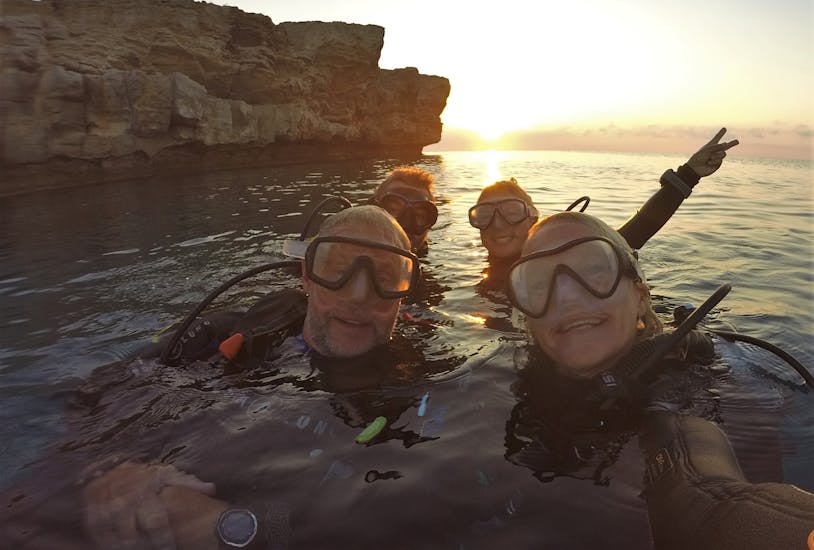 Eine Gruppe von Tauchern lacht nach einem Tauchgang bei Sonnenuntergang in die Kamera beim PADI Advanced Open Water Diver Kurs in Penera für zertifizierte Taucher mit Taba Diving Cyprus.