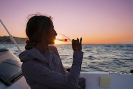 Un jeune femme profite du coucher de soleil tout en buvant du champagne lors d la balade privée en bateau au coucher du soleil avec snorkeling et champagne avec Serene Private Cruises.