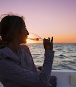 A girl enjoying the sunset while drinking champagne in the private sunset boat trip with snorkeling and champagne with Serene Private Cruises.