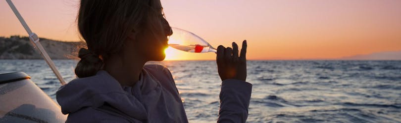 Un jeune femme profite du coucher de soleil tout en buvant du champagne lors d la balade privée en bateau au coucher du soleil avec snorkeling et champagne avec Serene Private Cruises.