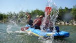 Freunde planschen mit Wasser auf dem Canadier-Rafting auf der Iller im Allgäu bei einer Tagestour mit Spirits of Nature Allgäu.
