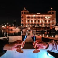 Una pareja brinda con una copa de vino tinto ofrecida durante nuestra excursión nocturna en barco por Ortigia y sus cuevas marinas con Dolci Escursioni.
