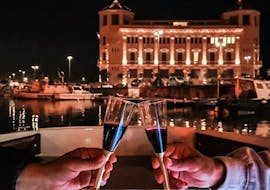 Ein Paar stößt mit einem Glas Rotwein auf unsere nächtliche Bootstour durch Ortigia und ihre Meeresgrotten mit Dolci Escursioni an.