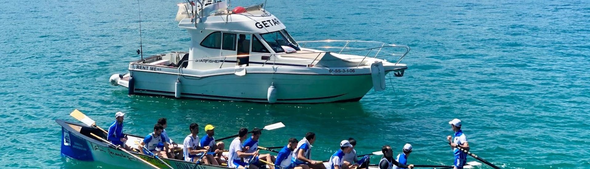 Menschen kajaken neben dem Boot während der Halbprivate Yacht-Tour zu den Klippen von San Sebastian mit Getari Charter San Sebastián.