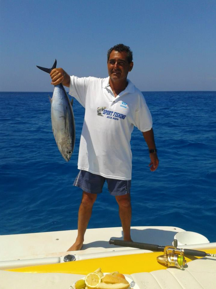 El patrón de la lancha RIB sujetando un pez recién pescado durante el paseo de pesca en barco desde Ayia Napa con Dolphin Boat Safari.