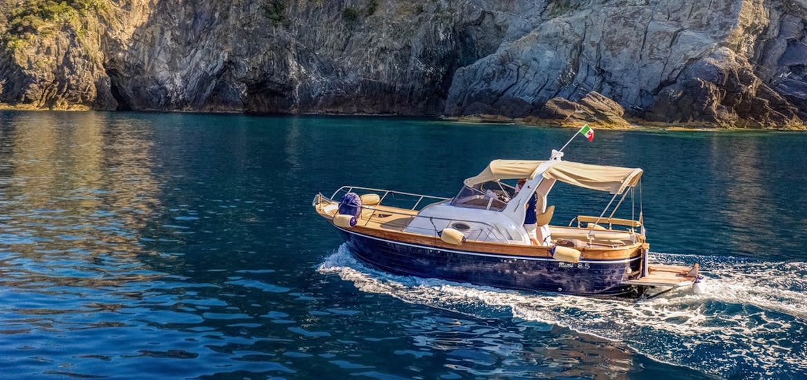La barca di San Giorgio Boats ferma in mare davanti agli scogli durante la Gita in barca privata a Porto Venere e alle Cinque Terre con pranzo.