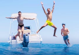Three young guys take a dip from our comfortable boat during a half-day private boat trip from San Vito Lo Capo to the Zingaro Nature Reserve with Marina Yachting Sicily San Vito Lo Capo.