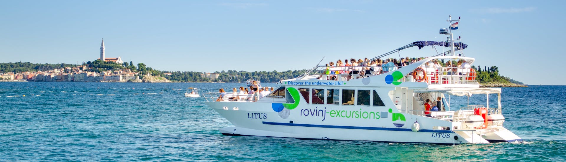 El barco LITUS en el agua cristalina de Istria durante el paseo en catamarán al atardecer alrededor de Rovinj con observación de delfines con Rovinj Excursions.