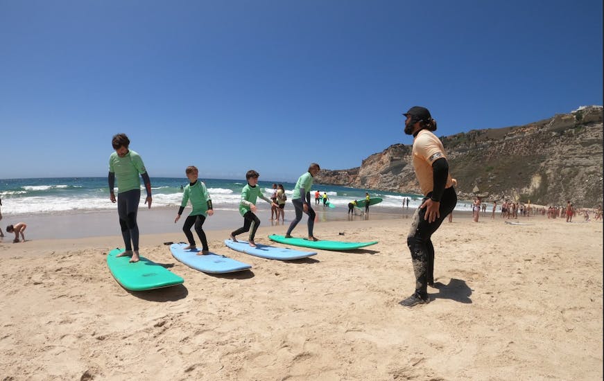 Photo of kids practicing their stand on the surf board during their Surf Lessons (from 6 y.) in Nazaré - All Levels with Zulla Surf School Nazaré.
