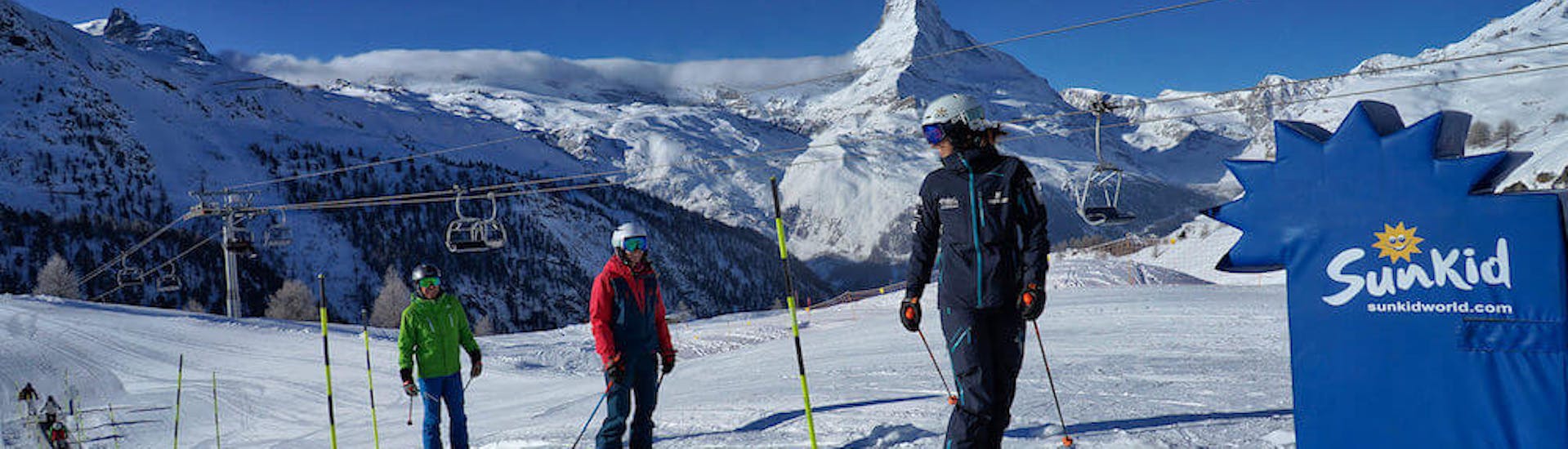 Maestro di sci e studenti che salgono sul tappeto magico durante le lezioni private di sci per principianti - 3 giorni con la Stocked Snowsports School Zermatt.
