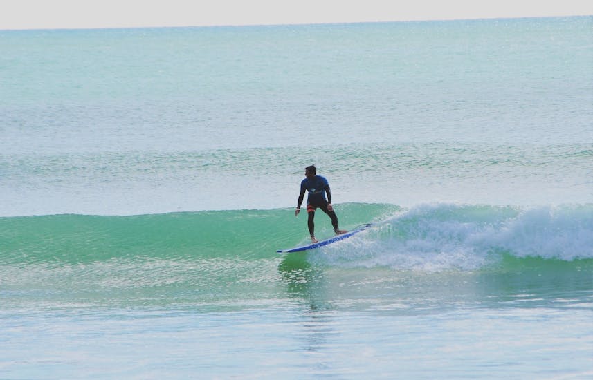 Un homme sur une vague pendant les cours de surf (à partir de 8 ans) à Praia da Galé à Albufeira avec Surf4Fun Albufeira.