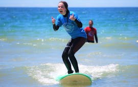 A girl smiles while surfing during the Private Surf Lessons (from 8 y.) on Praia da Galé in Albufeira with Surf4Fun Albufeira.
