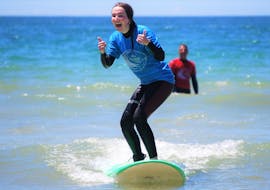 Ein Mädchen lächelt beim Surfen während der privaten Surfkurse (ab 8 J.) am Praia da Galé in Albufeira mit Surf4Fun Albufeira.