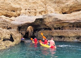 Delle persone esplorano una grotta naturale a bordo di un kayak durante il tour in Kayak alla grotta di Benagil da Praia de Albandeira con Surf4Fun Albufeira.
