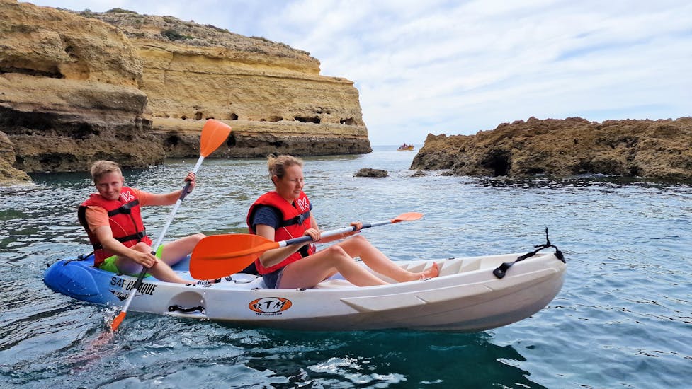 Deux personnes sortant d'une grotte naturelle sur leur kayak pendant le Kayak de mer à la grotte de Benagil de Praia de Albandeira avec Surf4Fun Albufeira.
