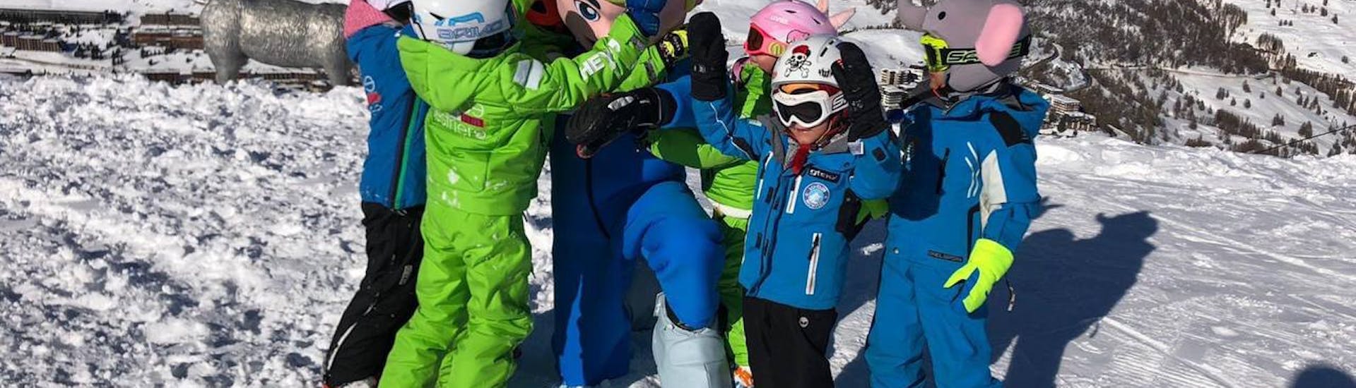 Kinderen juichen met de mascotte van hun snowboardlessen voor kinderen (4-8 jaar) voor beginners met Scuola Sci Vialattea Sauze d'Olux.