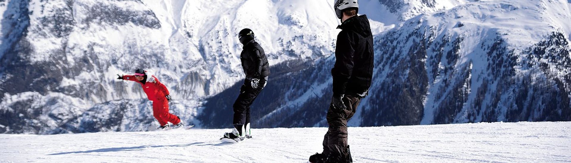 Due snowboarder seguono il loro istruttore di ESF Chamonix durante le lezioni private di snowboard per bambini e adulti di tutti i livelli.