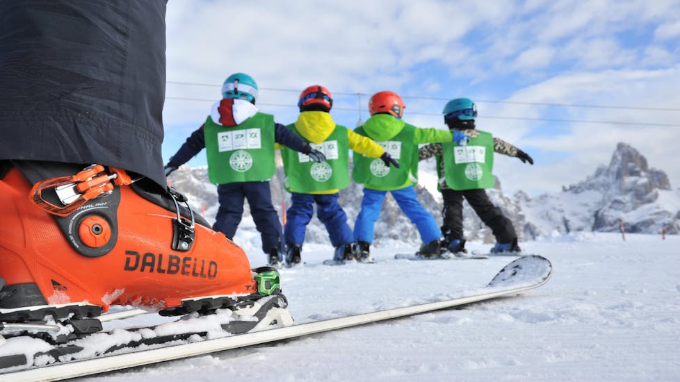 Un gruppo di bambini scia con un maestro durante le Lezioni di sci per bambini (4-5 anni) per principianti con Scuola Italiana Sci Dolomiti San Martino di Castrozza.