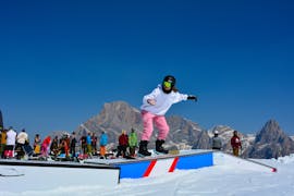 Un rideur essaie de nouvelles figures au snowpark de San Martino di Castrozza pendant les cours particuliers de snowboard pour tous les niveaux de la Scuola Italiana Sci Dolomiti San Martino di Castrozza.