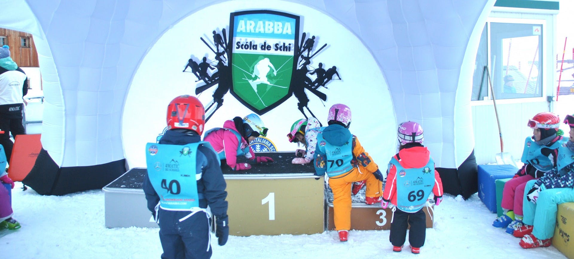 A group of kids on the chairlift in Arabba during the Full-day Kids Ski Lessons (from 4 y.) for Intermediate Skiers with Scuola Italiana Sci Arabba.