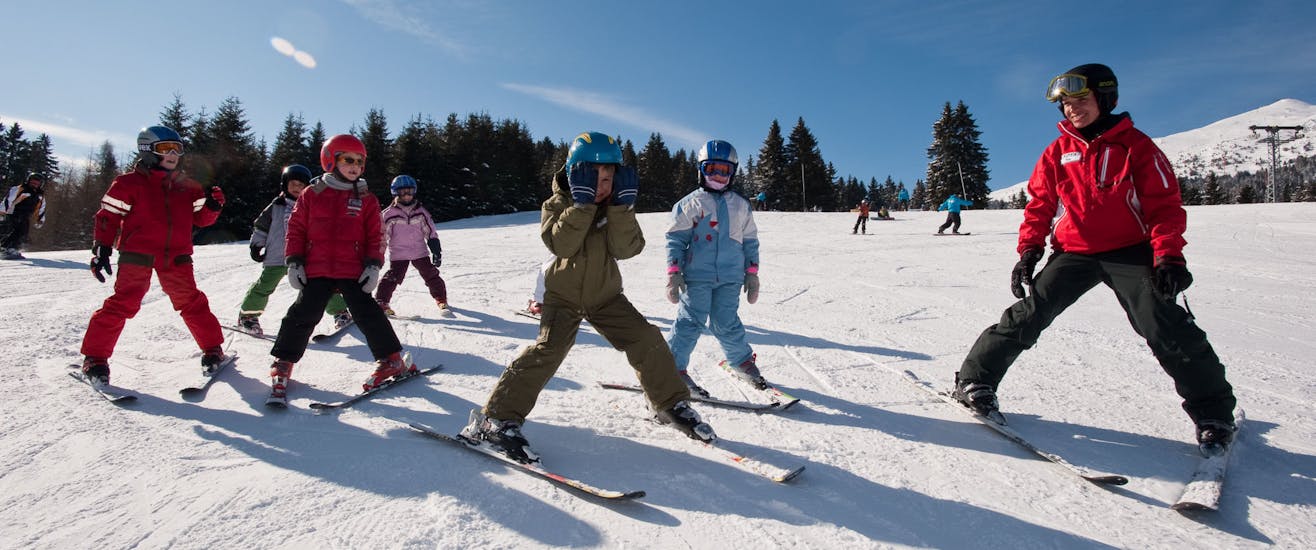 Kinderen skiën naar beneden in sneeuwploeg tijdens kinderskilessen voor beginners - weekend met skischool Nova.