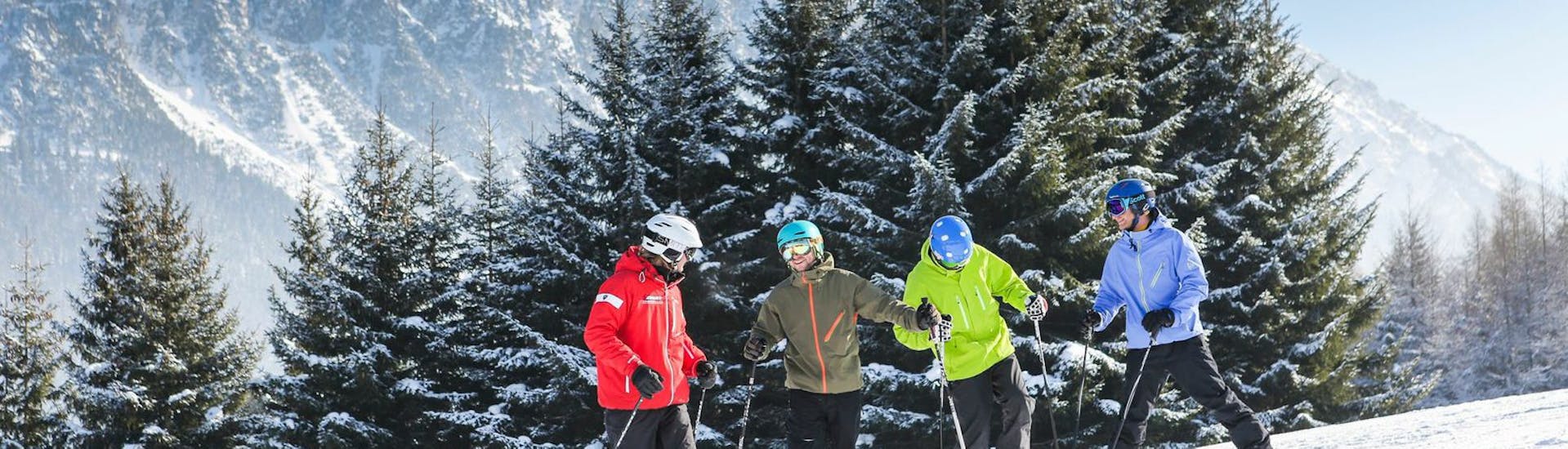 Un moniteur de ski et des élèves sur la piste pendant les cours de ski pour adultes débutants de Skischool Nova.