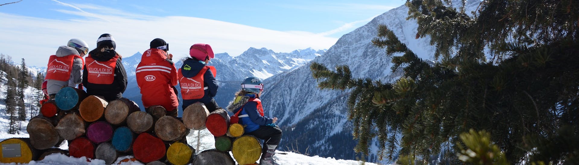 Foto di un gruppo di bambini che fanno una pausa con il loro maestro della Scuola di Sci Monte Bianco Courmayeur durante le Lezioni private di sci per bambini (dai 4 anni) per tutti i livelli.