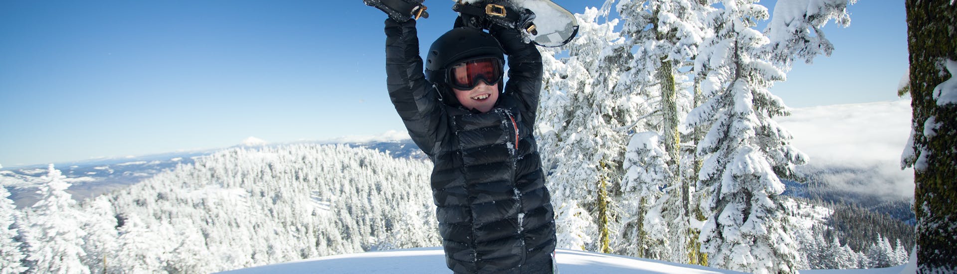 Ein Snowboarder hebt sein Board in die Luft beim Snowboardkurs für Kinder (ab 7 J.) & Erwachsene aller Levels mit der Schneesportschule ON SNOW Feldberg.