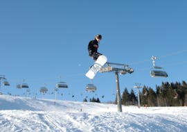 A snowboarder jumps across the piste during private snowboard lessons for kids (from 7 yrs) & adults of all levels with the ON SNOW Feldberg snow sports school.
