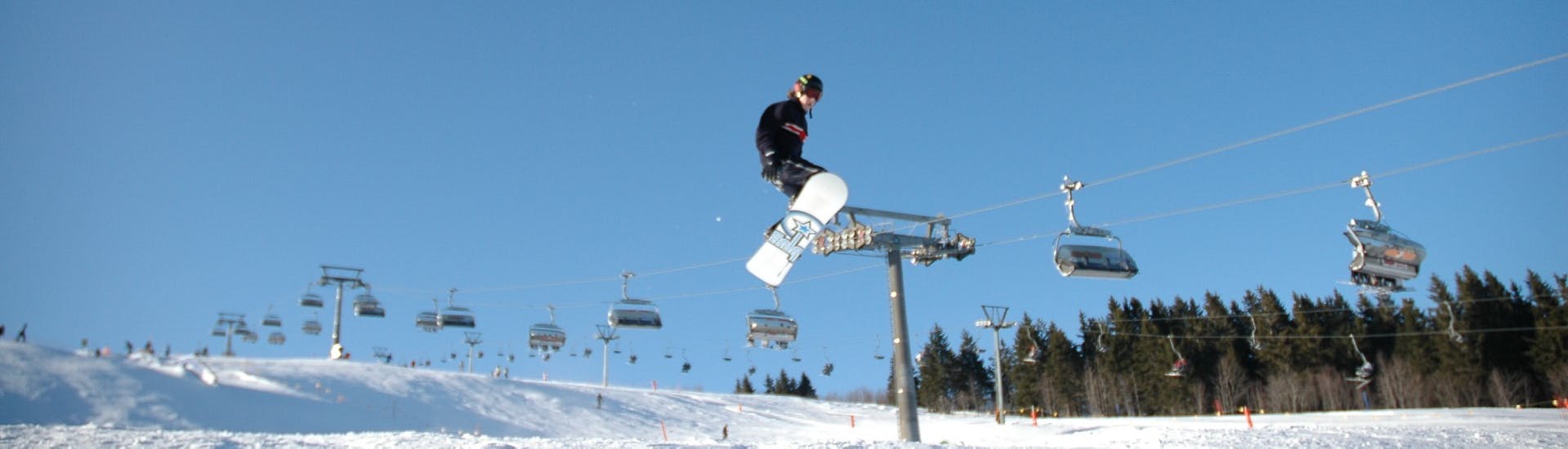 Un snowboardeur saute à travers la piste pendant un Cours particulier de snowboard pour Enfants (dès 7 ans) & Adultes pour Tous Niveaux avec l'école de ski ON SNOW Feldberg.