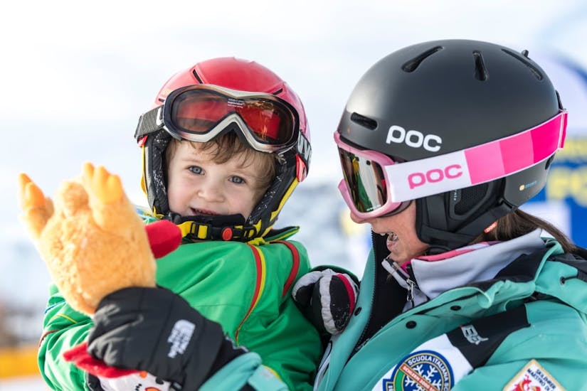 Skilehrerin hält Kind in den Armen beim Kinder-Skikurs "Yeti Club" für Anfänger mit Skischule Schlern 3000.