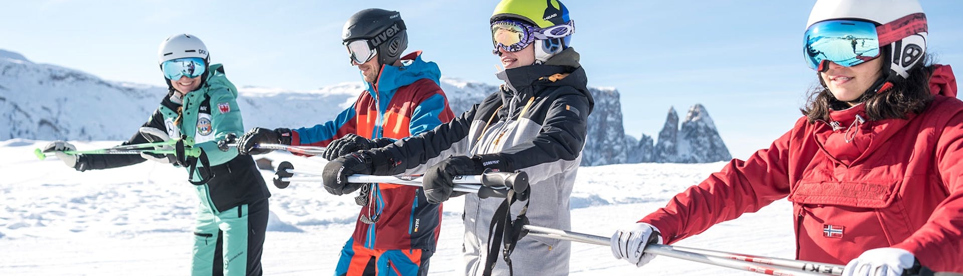 Volwassenen houden zich vast aan een stang tijdens de skilessen voor volwassenen voor alle niveaus met skischool Schlern 3000.