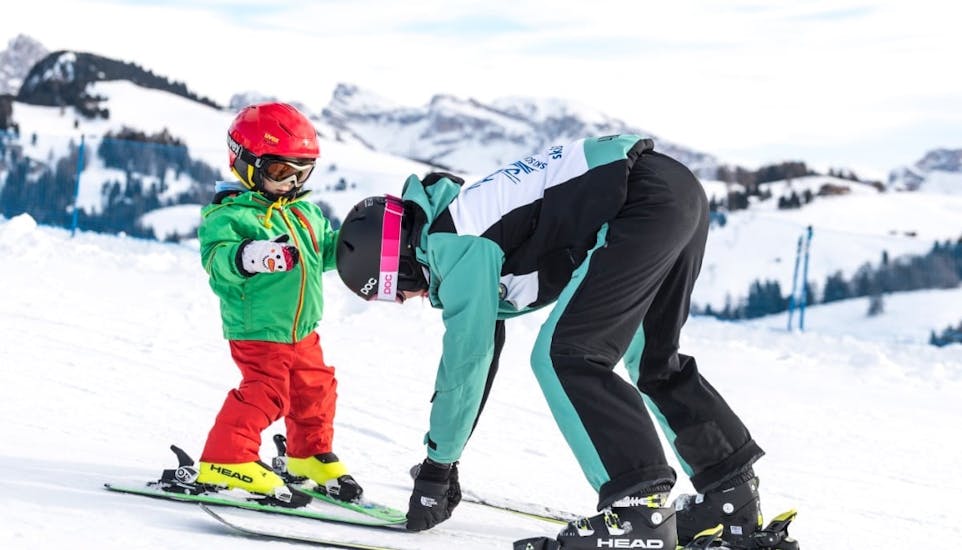 Skilehrer richtet Skier von Schüler in den Schneepflug während Privater Kinder-Skikurs für alle Levels mit Skischule Schlern 3000.
