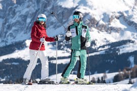 Il maestro di sci indica una direzione con i bastoncini durante la lezione di sci private di sci per adulti per tutti i livelli con Skischool Schlern 3000 Alpe di Siusi.