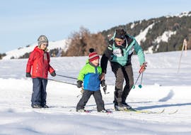 Kinder mit Instruktor auf der Langlaufloipe beim Langlaufkurs für alle Levels mit Skischule Schlern 3000.
