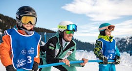 Bambini e maestro di sci che si tengono al palo durante le lezioni di sci per bambini di tutti i livelli - Saltria con la scuola di sci Schlern 3000.
