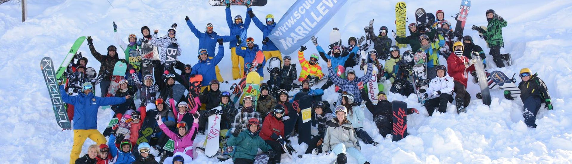 Un grande gruppo di riders posa di fronte alla fotocamera con i maestri della Scuola di Sci Marilleva durante le Lezioni di snowboard (dai 4 anni) per tutti i livelli.
