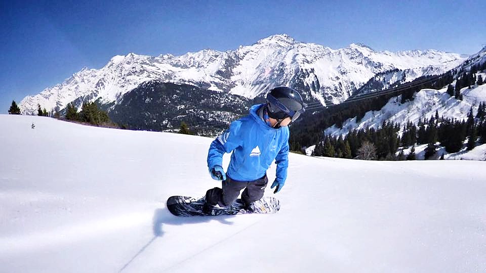 A snowboarder is going down a slope during their Private Snowboarding Lessons for Kids & Adults with Freedom Snowsports Mont Blanc.