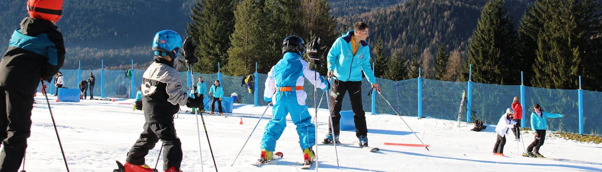 Drei Kinder und ein Lehrer beim Privat-Skikurs für Kinder (ab 3 Jahren) für alle Levels mit der Scuola Sci Antelao San Vito di Cadore.