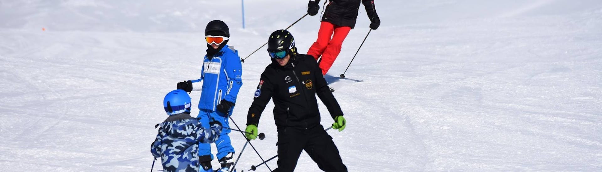 Maestro di sci e studenti che scendono con lo spazzaneve durante le lezioni di sci per bambini alle prime armi con Ski Cool St. Moritz.