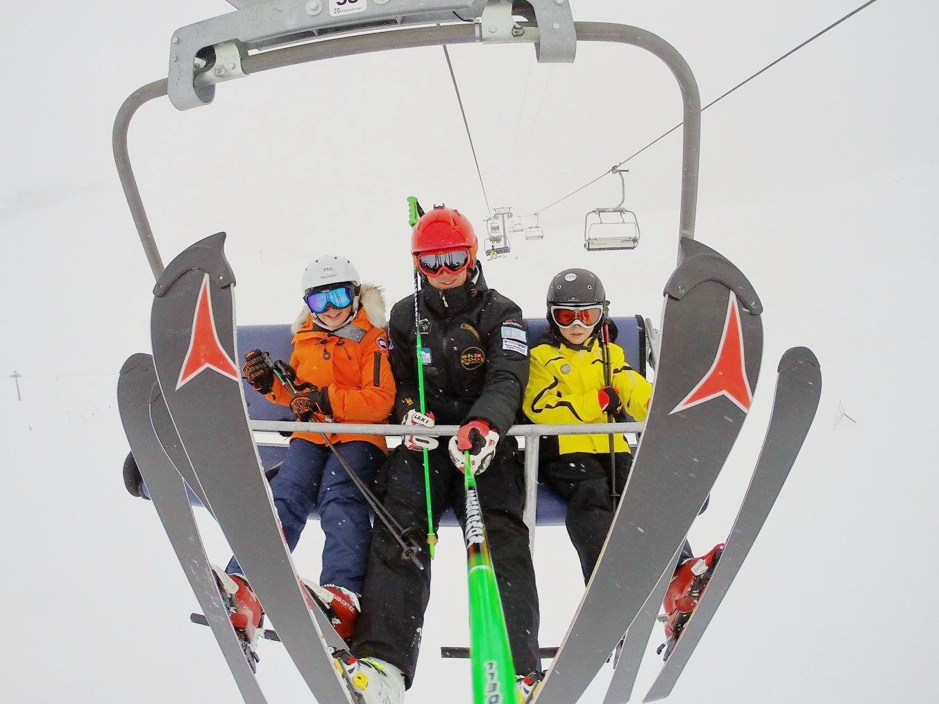 Instructor and students sitting in a chairlift during the Kids Ski Lessons (5-15 y.) for Experienced Skiers with Ski Cool St. Moritz.