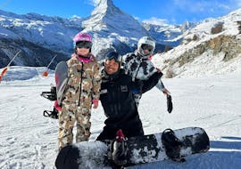 Un instructor de PDS Snowsport posa con dos snowboarders frente al Matterhorn durante sus clases particulares de snowboard para niños y adultos de todos los niveles.