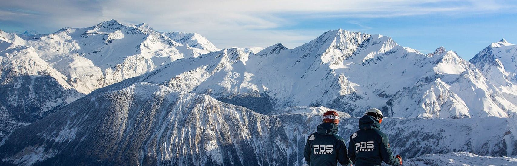Deux moniteurs de PDS Snowsport regardent vers les monts enneigés avant de commencer leur Cours particulier de snowboard pour Tous niveaux.