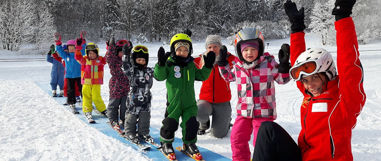 Kids and ski instructor holding hands in the air during Kids Ski Lessons (4-14 y.) for All Levels With G&S snowsportschool Mitterdorf.