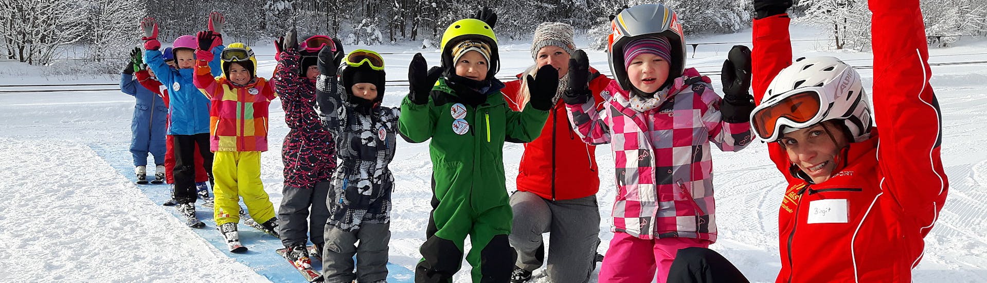 Kinder und Skilehrer halten Hände in die Höhe während Kinder-Skikurs (4-14 J.) für alle Levels mit Schneesportschule Mitterdorf.