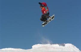 Snowboarder springt op de piste tijdens de privéles snowboarden voor kinderen en volwassenen op alle niveaus bij G&S sneeuwsportschool Mitterdorf.