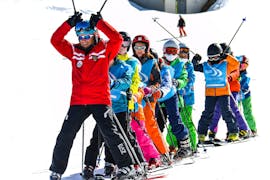 Een groep kinderen poseert voor de camera met hun instructeur tijdens de skilessen voor kinderen (5-12 jaar) voor alle niveaus met Scuola di Sci Pila.