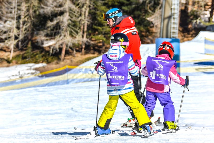 A couple of kids are following their instructor from Scuola di Sci Pila during the Private Ski Lessons for Kids (from 3 y.) of All Levels.