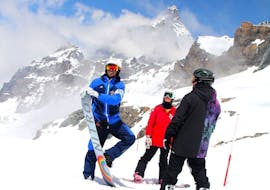 Un maestro della Scuola di Sci Pila posa di fronte alla fotocamera con due partecipanti delle Lezioni private di snowboard per tutte le età e i livelli.